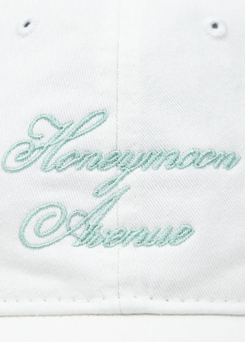 Close-up detail of Ariana Grande Honeymoon Avenue white dad hat featuring pastel embroidered script typography