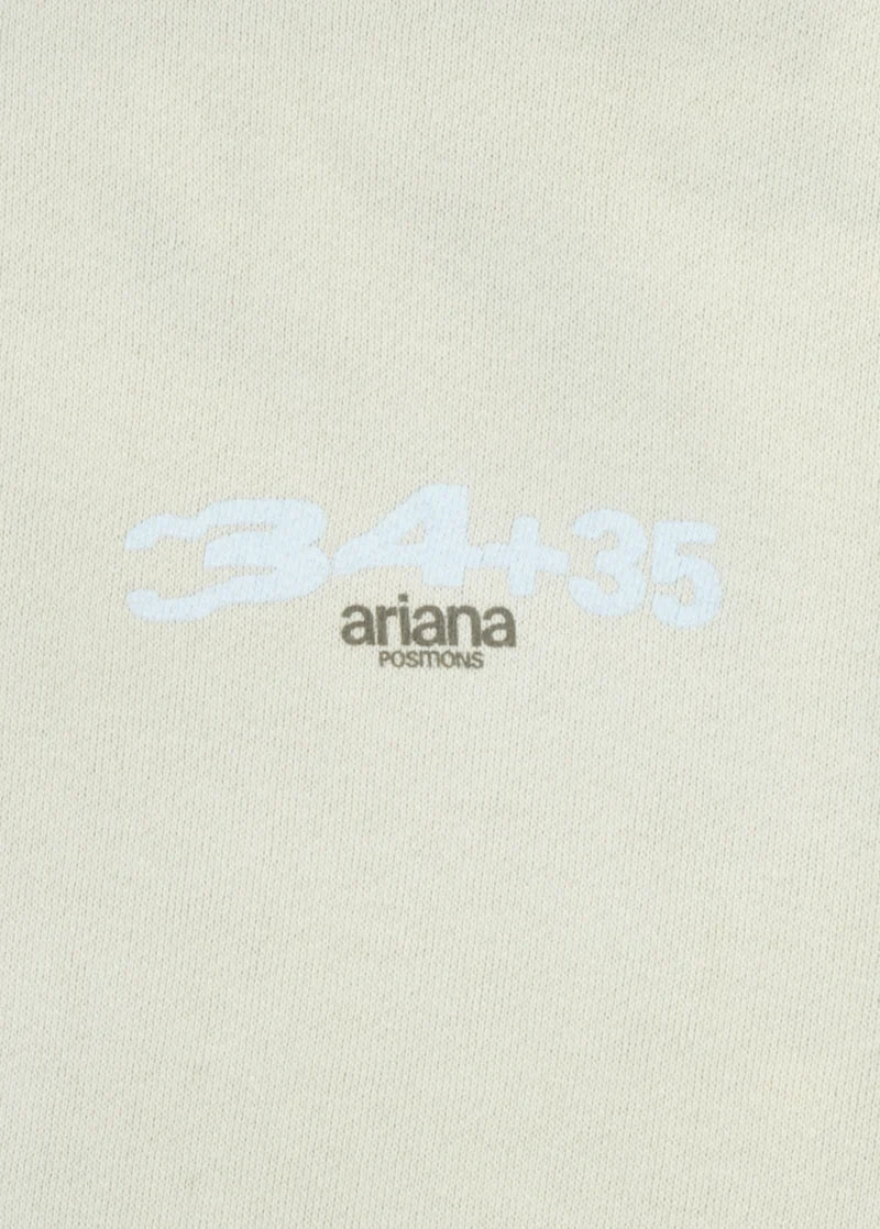 Closeup detail of Ariana Grande 34+35 positions logo print on cream hoodie with soft glam aesthetic