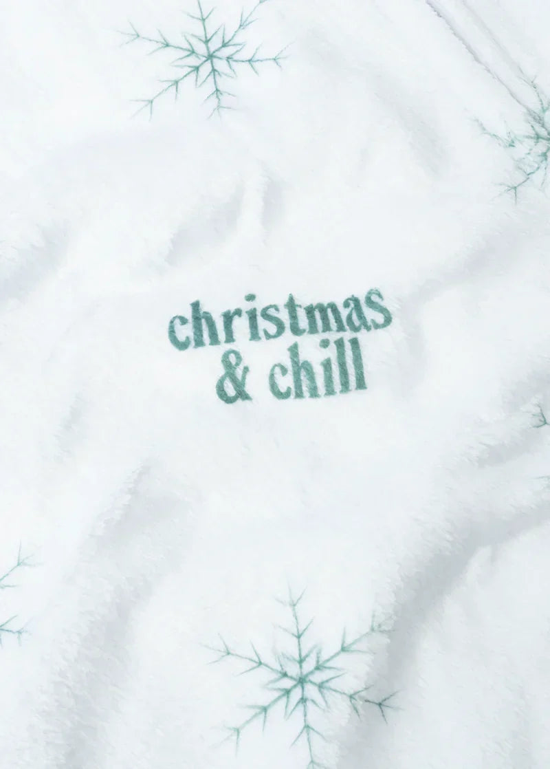 Close-up detail of Ariana Grande Christmas and Chill white fleece fabric with teal holiday text and snowflakes