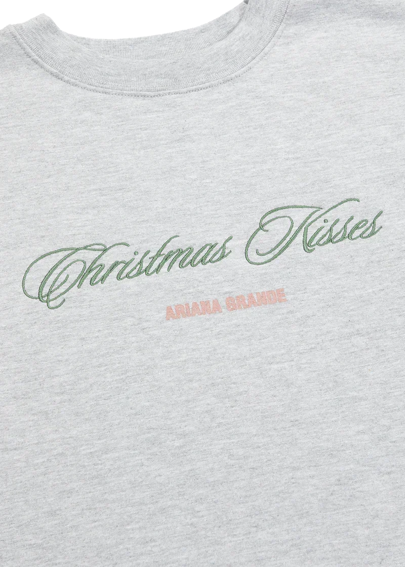 Ariana Grande Christmas Kisses crewneck close-up with green embroidered holiday script and logo detail