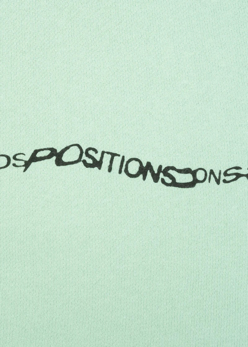 Closeup detail of Ariana Grande Positions repeating text logo on mint oversized hoodie