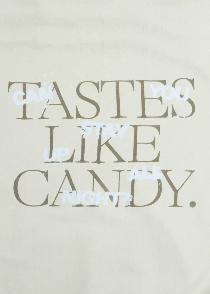 Closeup detail of Ariana Grande Tastes Like Candy reflective graphic print on cream oversized hoodie